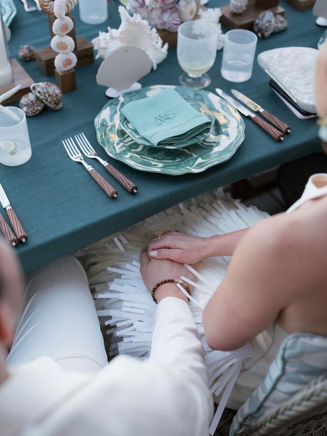 Bride and groom holding hands at a sea-inspired reception table at an Easton Events wedding in St. Tropez.