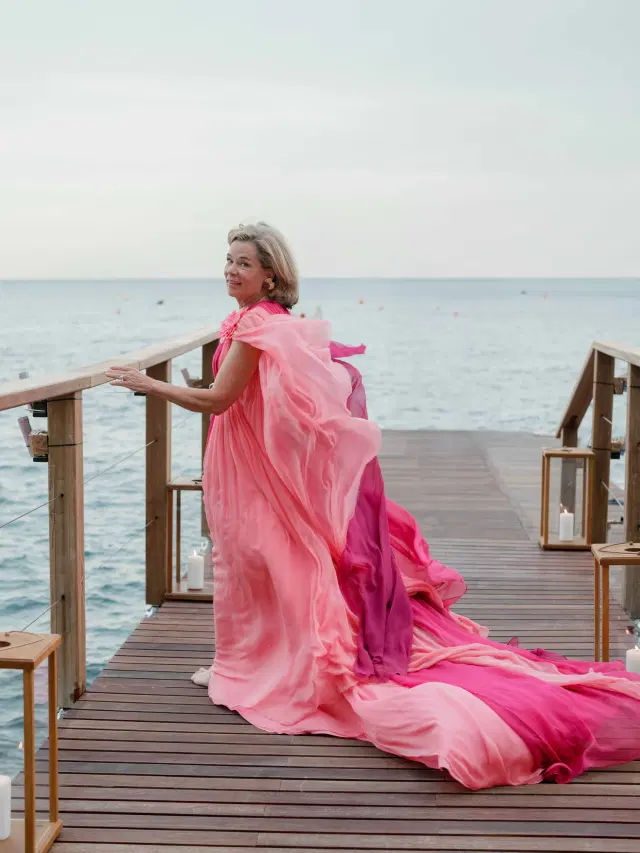 Wedding guest in a flowing pink gown on a candlelit seaside pier at an Easton Events wedding on the Amalfi Coast.