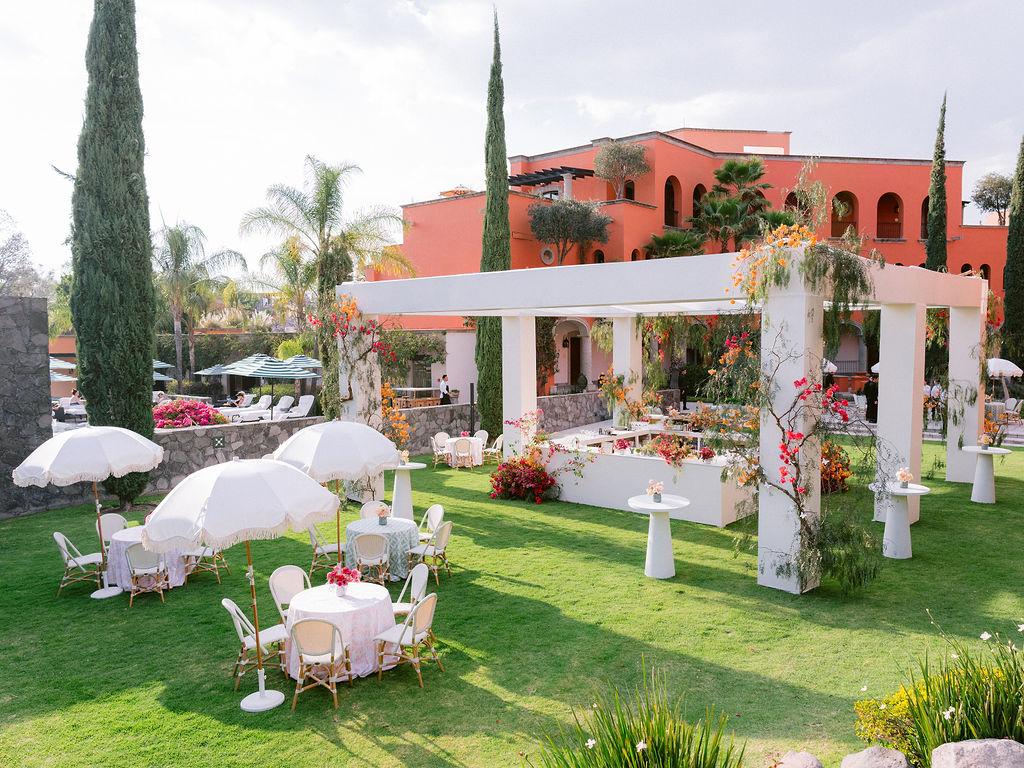 Outdoor wedding reception on a manicured lawn with colorful florals and white parasols in San Miguel de Allende, Mexico.